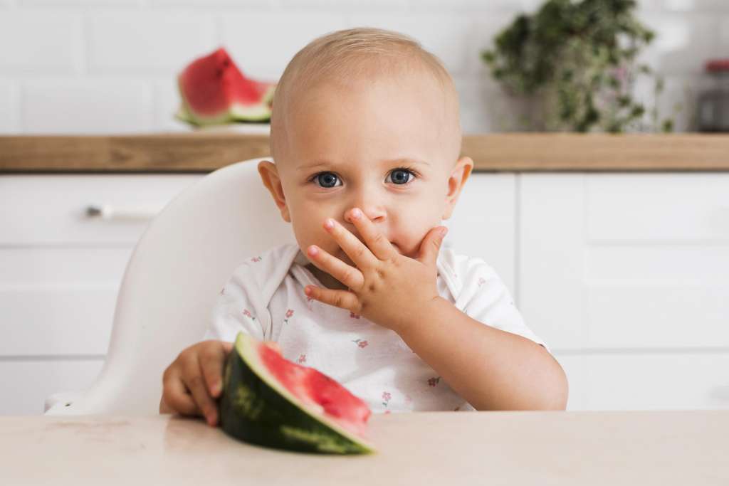 bebê comendo melancia para aliviar sintomas da primeira dentição