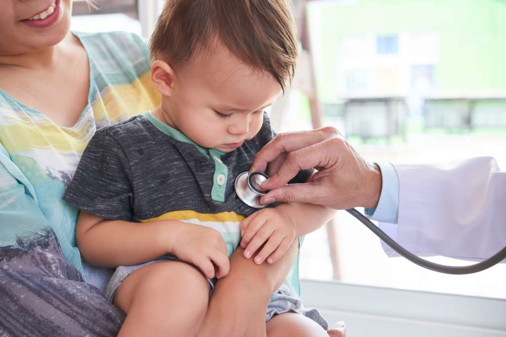 médico examinando bebê no colo da mãe