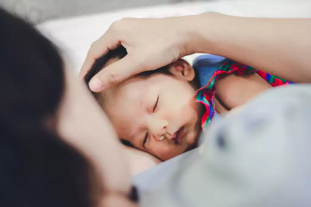 Mãe tentando fazer seu filho dormir devido ao impacto da primeira dentição no sono.